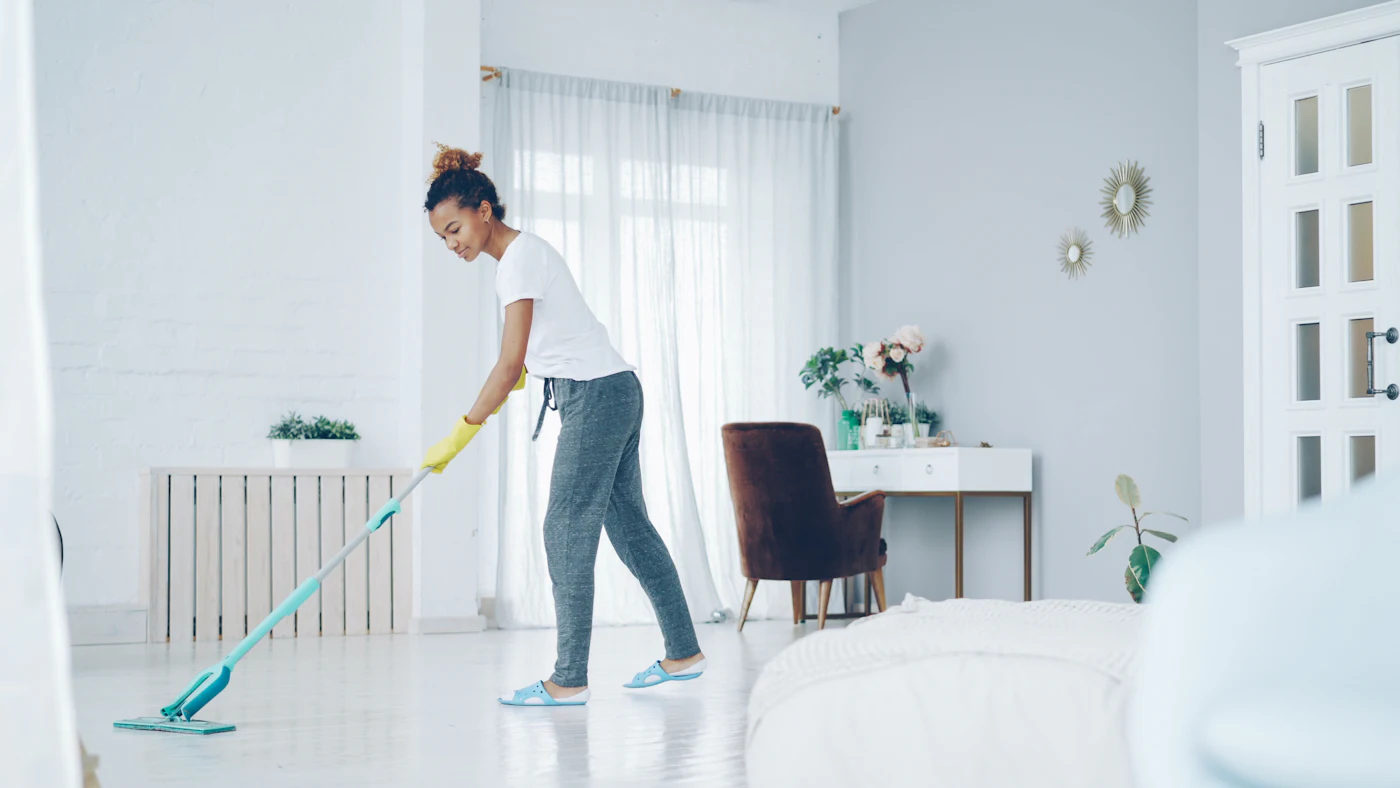 Professional cleaner mopping the floor of a bright modern living room during a Hypermaids house cleaning visit
