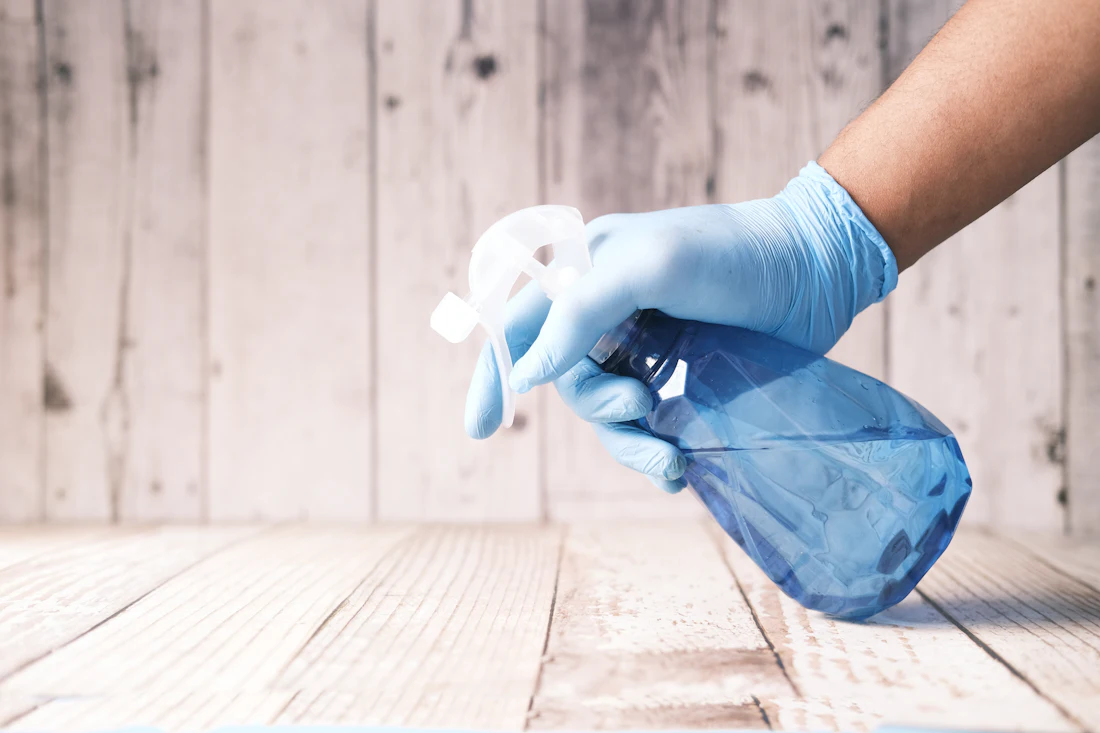 Insured professional cleaner sanitizing a home surface with eco friendly cleaning spray